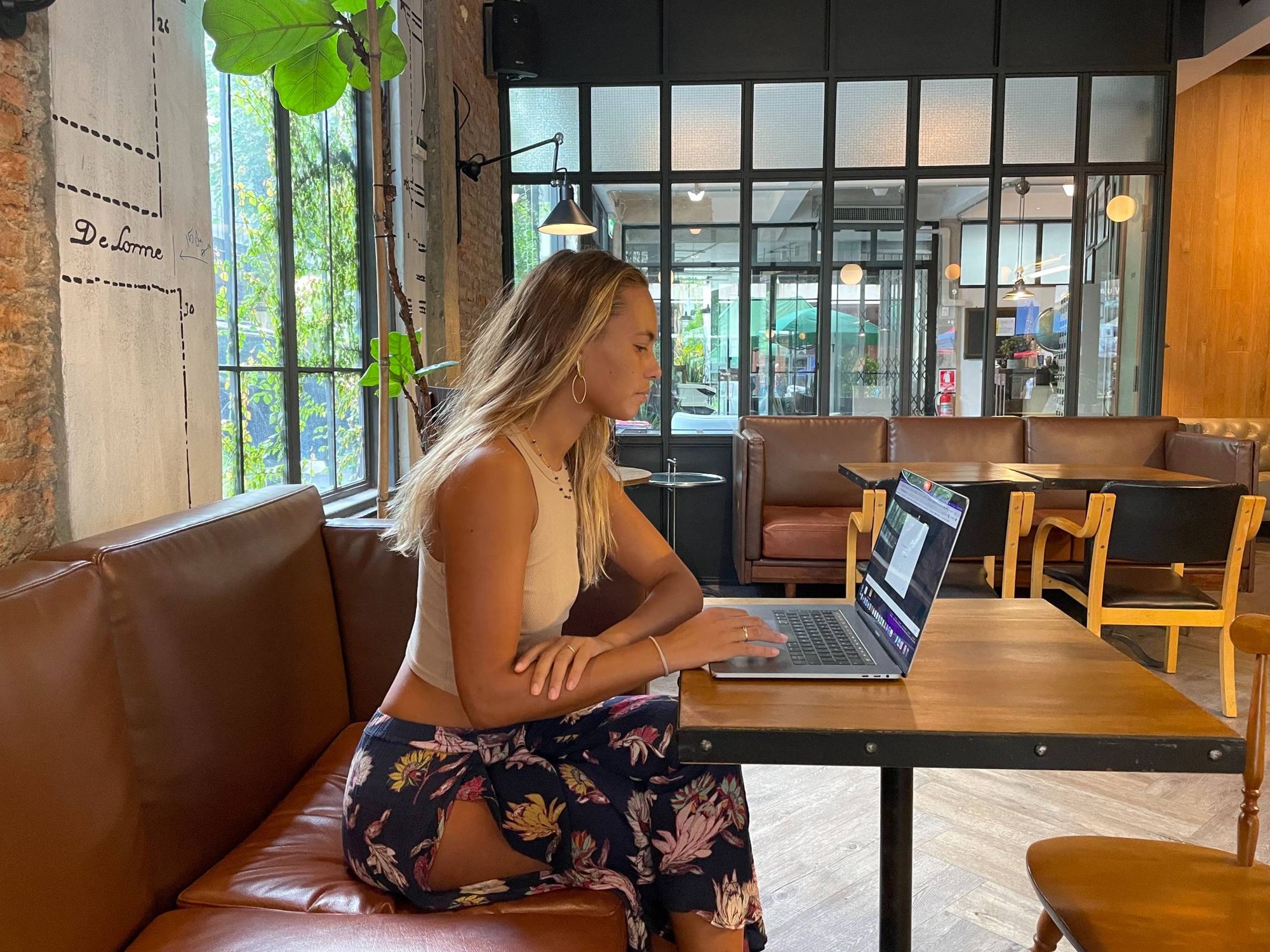 Artisan Cafe, Chiang Mai, Thailand. Wooden tables and black chairs, leather couch, plant, glass door