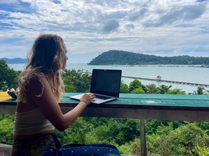 Digital Nomad working on her laptop at Rasta View Bar, Koh Chang, Thailand. Mountainous, jungle, ocean.