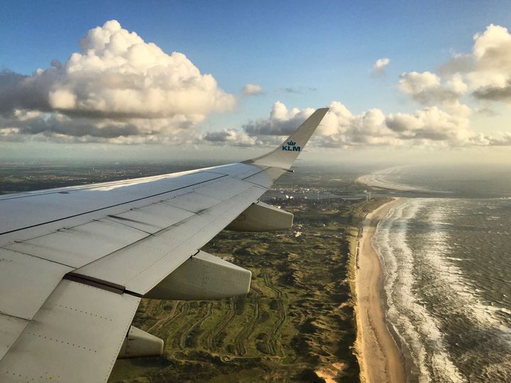 KLM airplane, the Netherlands from above, coastline, ocean, beach, grass, white clouds, blue sky