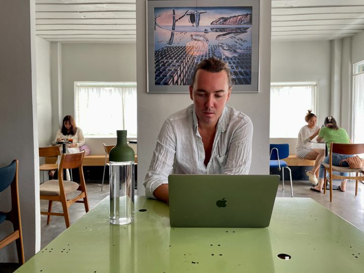 Café Khagee, Chiang Mai, Thailand, green desk with an apple MacBook, jar of water, painting on the wall